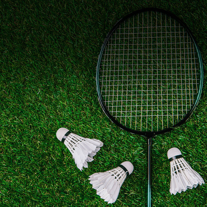  badminton racquet and shuttlecocks in the grass